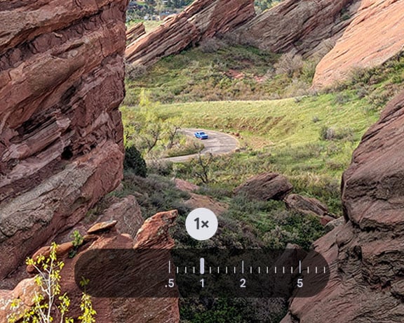 A panoramic outdoor scene features a blue car on a winding road