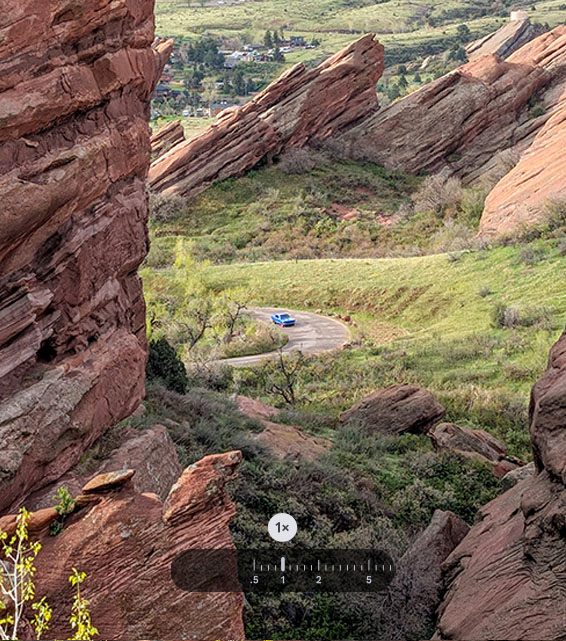 A panoramic outdoor scene features a blue car on a winding road