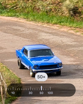 A close-up view of a bright blue vintage car parked on a dirt or gravel road