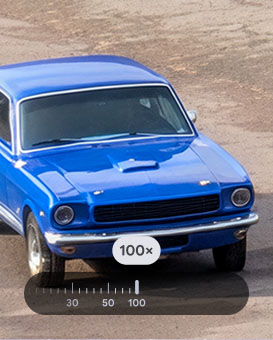 A highly zoomed-in view of a bright blue vintage car, parked on a gravel surface showing the power of Super Res Zoom on Pixel